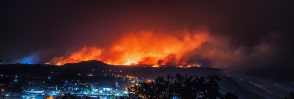 Wildfire burning in hills behind a town